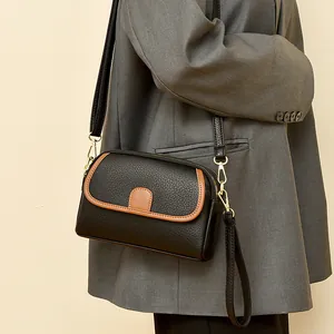Chic black litchi leather crossbody bag with brown trim and gold hardware for women