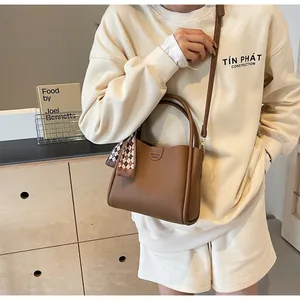 Detail of vintage brown textured leather tote bag with silk scarf and logo debossing