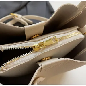Detail showing the creamy white lychee texture leather interior and golden zipper of the bag