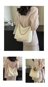 Detail of creamy white leather hobo bag with thick gold chain and small coin purse attached
