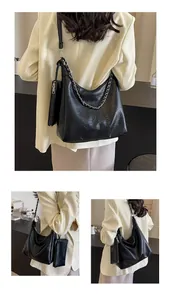 Detail of black pleated leather tote bag with silver chain and matching pouch on model