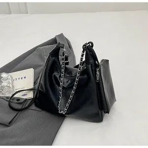 Close-up of black leather bag with silver chain strap and a detachable mini pouch