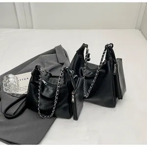 Detail of black pleated faux leather tote bag with metal chain strap and matching pouch
