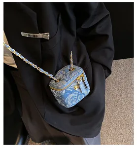 Close-up of mini blue denim crossbody bag with quilted rose pattern and gold chain