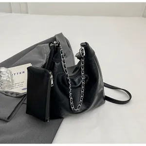 Detail of black pleated tote bag with silver chain and matching zipper pouch accessory