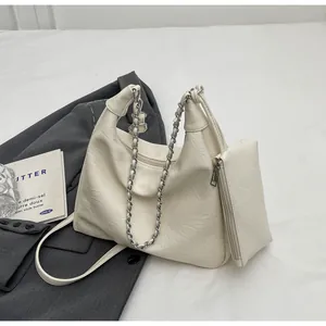 Detail of cream pleated shoulder bag with silver chain strap and small matching pouch