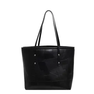 Close-up of black tote bag with geometric patchwork and silver rivet accents