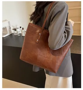 Close-up of a large brown leather tote bag with geometric stitching and silver rivets