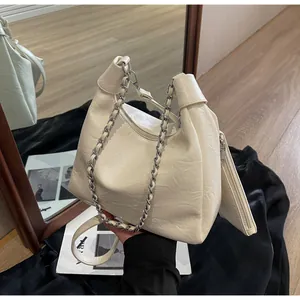 Detail view of the pleated texture, silver chain, and matching coin pouch on the cream bag
