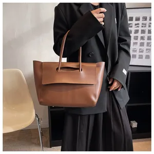Detailansicht der braunen Leder-Tote-Bag, von einem Model in minimalistischer Umgebung gehalten