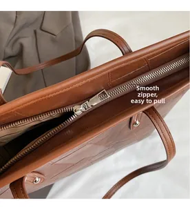 Close-up of a smooth silver zipper and embossed leather texture on a brown tote bag