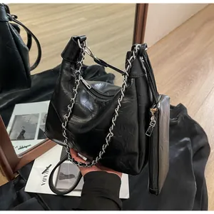 Detail of black pleated shoulder bag featuring a chunky silver chain and mini coin purse