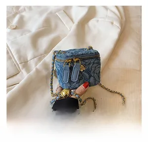 Detailed macro shot of blue quilted denim mini bag with gold chain and floral charm detail