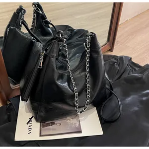 Detail of black hobo bag in glossy leather with silver chain and detachable pouch