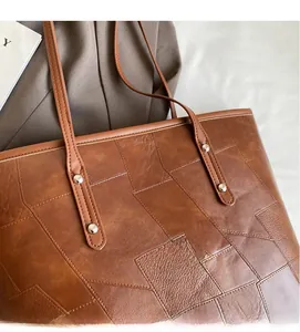 Close-up of geometric patchwork texture and silver metal rivets on brown tote bag