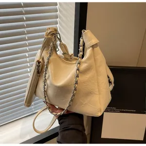 Detail of cream pleated leather dumpling bag with metal chain and mini pouch attachment