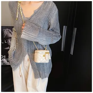Close-up of a beige quilted vanity bag with gold chain and floral metal detail