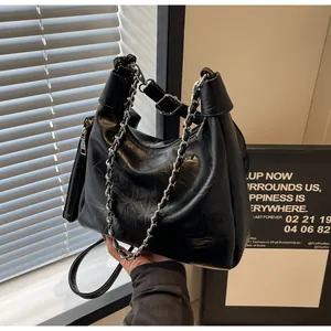 Close-up of black leather hobo bag with silver chain and a matching small pouch charm