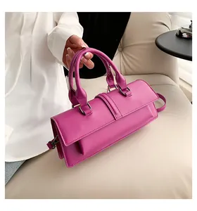 Nahaufnahme einer magentafarbenen rechteckigen Handtasche auf einem cremefarbenen Sofa