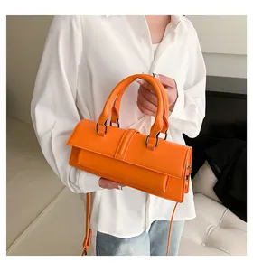 Details einer leuchtend orangefarbenen Ledertasche kombiniert mit weißem Hemd und Jeans