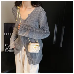Detail of white quilted mini vanity bag featuring gold chain strap and dual zipper closure