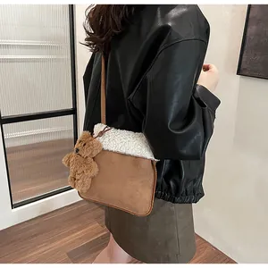 Detail of vintage brown suede crossbody bag with white faux shearling trim and bear charm
