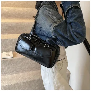 Detalle de bolso de hombro negro brillante con bolsillos frontales dobles y hebillas plata
