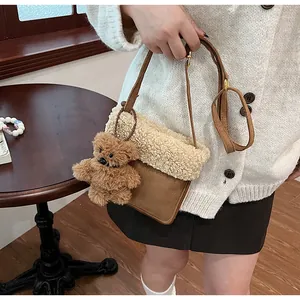 Detail of faux shearling crossbody bag with a plush bear charm and leather strap