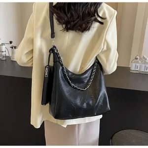 Detail of black pleated shoulder bag with silver chain and detachable small pouch