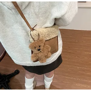 Detail of faux suede crossbody bag with fleece trim and cute brown plush bear charm