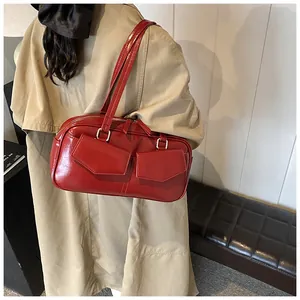 Detalle del bolso de hombro rojo brillante con bolsillos frontales y hebillas de aro plateado