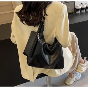 Detail of black leather hobo bag with mini pouch and silver chain strap on shoulder