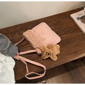 Detailed shot of pink shearling shoulder bag with a teddy bear charm on a wooden bench