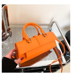 Nahaufnahme der orangefarbenen Handtasche mit Rundgriffen und dunklen Metallbeschlägen