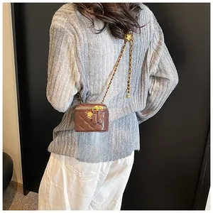 Detail view of mini quilted crossbody bag in dark brown with gold flower zipper and chain