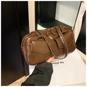 Detalle del bolso de hombro marrón oscuro brillante con dos bolsillos delanteros