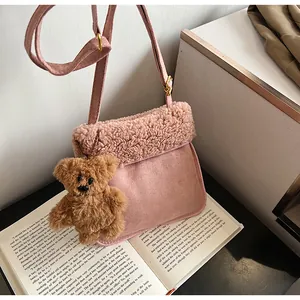 Detailed close-up of pink faux suede and shearling tote with cute plush bear charm
