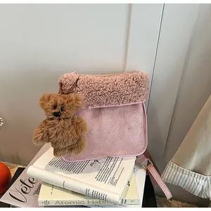 Close-up of pink faux suede and shearling crossbody bag with a brown teddy bear charm