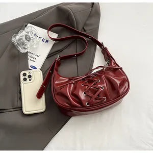 Detail of dark red crescent bag with silver metallic eyelets and lace-up decoration