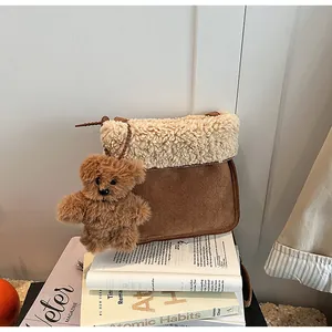 Detail of faux suede shoulder bag with cream shearling trim and plush bear charm