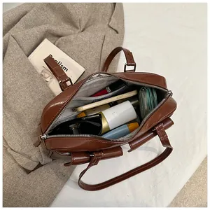 Detalle del interior de gran capacidad con accesorios en bolso de hombro marrón