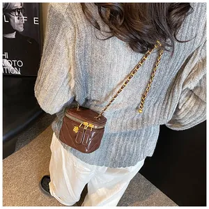 Close-up of brown quilted mini box bag with golden floral charm and metal chain