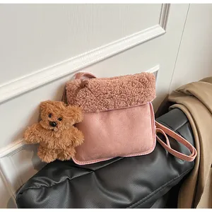 Detail of pink faux suede crossbody bag with plush trim and cute teddy bear pendant