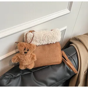 Detail of faux suede shoulder bag with white fleece trim and cute brown bear pendant