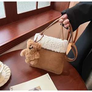 Detail of suede tote bag featuring fuzzy fleece trim and cute teddy bear pendant charm