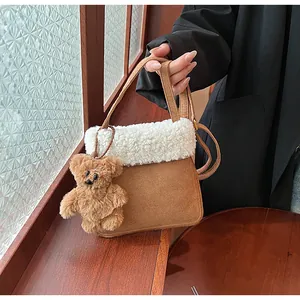 Detail of faux suede tote with shearling trim and cute brown plush bear charm