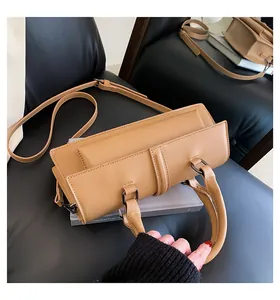 Detailansicht einer kamelfarbenen Handtasche aus Leder mit verstellbarem Riemen auf Büchern