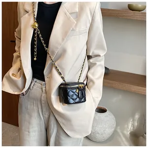 Detail of a mini quilted black crossbody bag featuring a gold ball chain adjuster