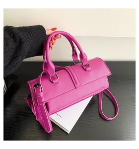 Detail der magentafarbenen Handtasche mit Doppelgriffen und dunklen Beschlägen auf Tisch