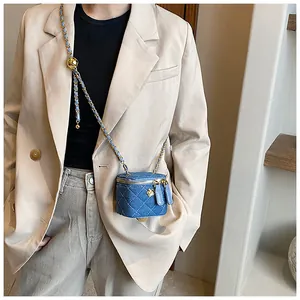 Detailed close-up of a blue denim quilted mini box bag with gold metal floral accent